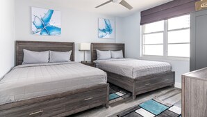A bedroom with two beds, a ceiling fan, artwork, a window with curtains, and a dresser. - 2BR 2BA AMAZING NEWLY RENO BEACHFRONT APT W/BEACH VIEW (Hollywood)