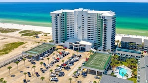 Un hotel moderno con piscina, cancha de tenis y vista al mar.