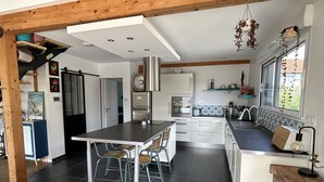 Une cuisine moderne dotée d’un îlot central, d’appareils électroménagers en acier inoxydable et d’un coin repas avec des chaises.
