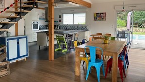 Une cuisine spacieuse avec un coin repas, un escalier en bois et une vue sur l’extérieur.