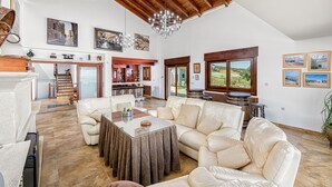 A spacious living area with a high ceiling, a fireplace, and a view of the outdoors.