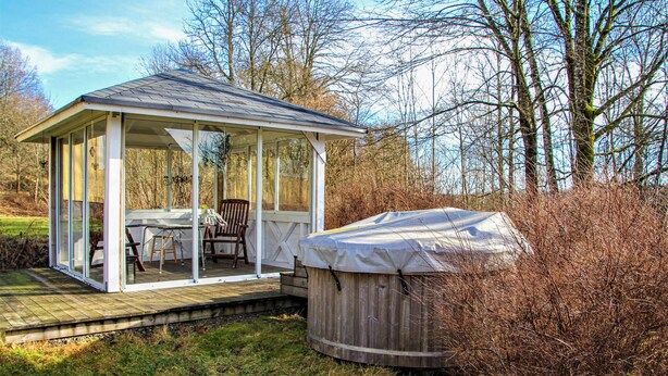 Un belvédère entièrement vitré, avec une table et des chaises, un jacuzzi et une terrasse en bois.