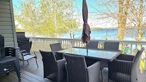 A covered outdoor deck with wicker furniture and a grill.