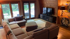 A cozy living room with a large sectional sofa, a flat-screen TV, and a wooden ceiling. - Stratton Mountain Home Hot Tub, Fire Pit and walk to the mountain. (Stratton)