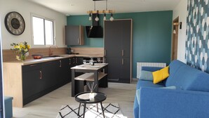 A modern kitchen with a dining area, a blue sofa, and a patterned rug.