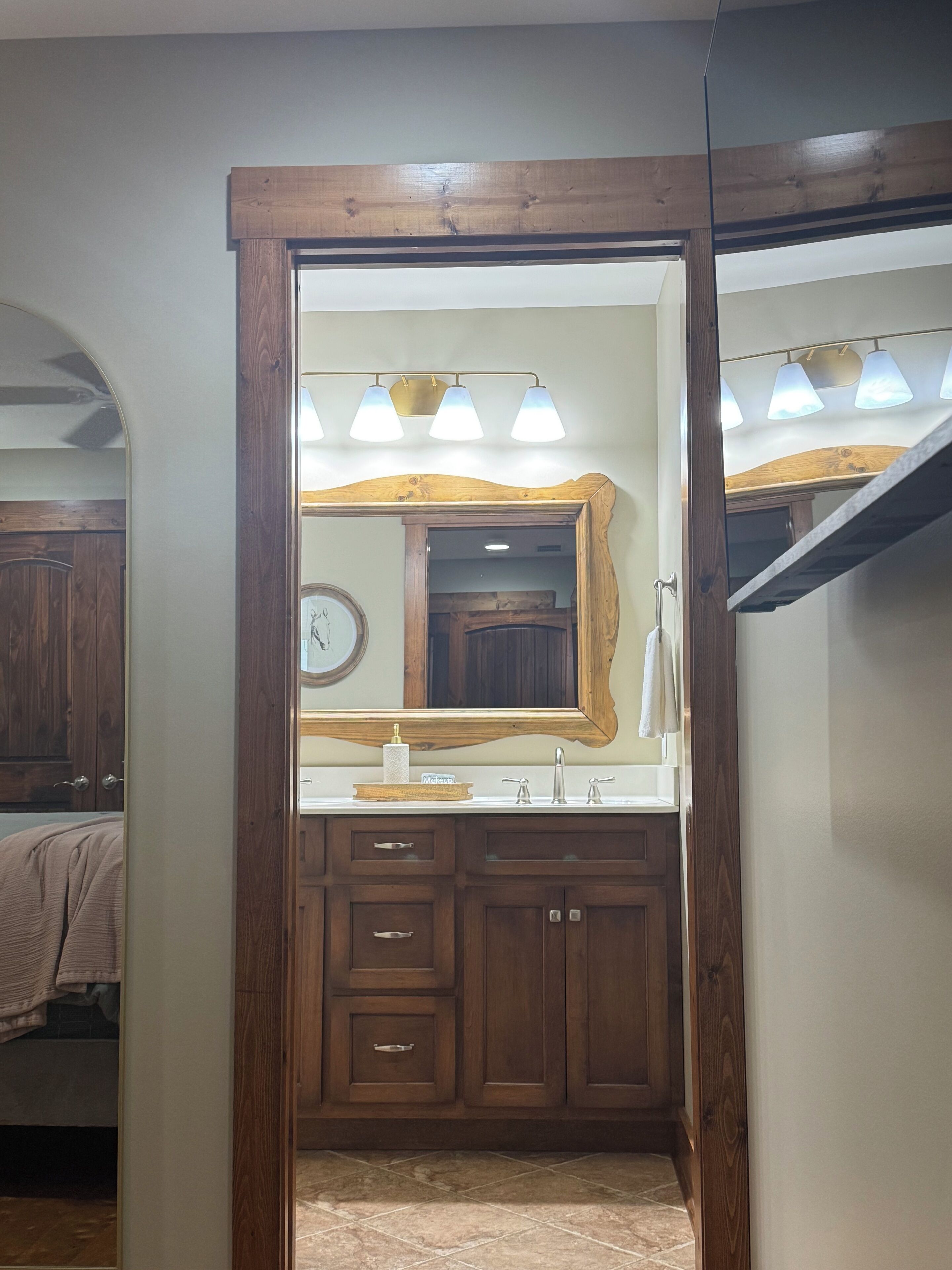 A bathroom with a wooden vanity, a large mirror, and a modern light fixture.