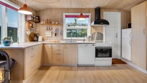Une cuisine moderne avec des meubles en bois, un four encastré, un lave-vaisselle et des luminaires suspendus.