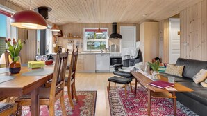 Un salon chaleureux comprenant un coin repas, une cuisine et un canapé en cuir noir.