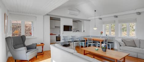 A spacious living area with a sofa, a dining table, and a kitchen in the background.
