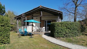 A wooden cabin with a covered patio, outdoor seating, and a well-maintained garden. - House 4 pers. in residence with swimming pools, wifi (Parentis-en-Born)