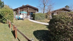 A two-story building with a covered patio area, a gravel path, and a wooden fence. - House 4 pers. in residence with swimming pools, wifi (Parentis-en-Born)