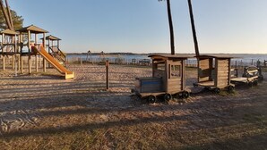 A beach playground with a slide and swings, a wooden playhouse, and a small cart. - House 4 pers. in residence with swimming pools, wifi (Parentis-en-Born)