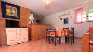 A cozy kitchen with wooden cabinets, a dining table with chairs, and a tiled floor. - House 55m2, large swimming pool (BUZIGNARGUES)