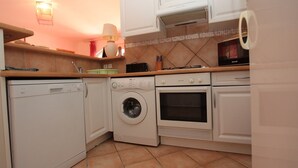 A compact kitchen with a washing machine, oven, and microwave. - House 55m2, large swimming pool (BUZIGNARGUES)