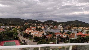 Uma vila costeira com edifícios residenciais, um porto de iates e montanhas ao fundo.