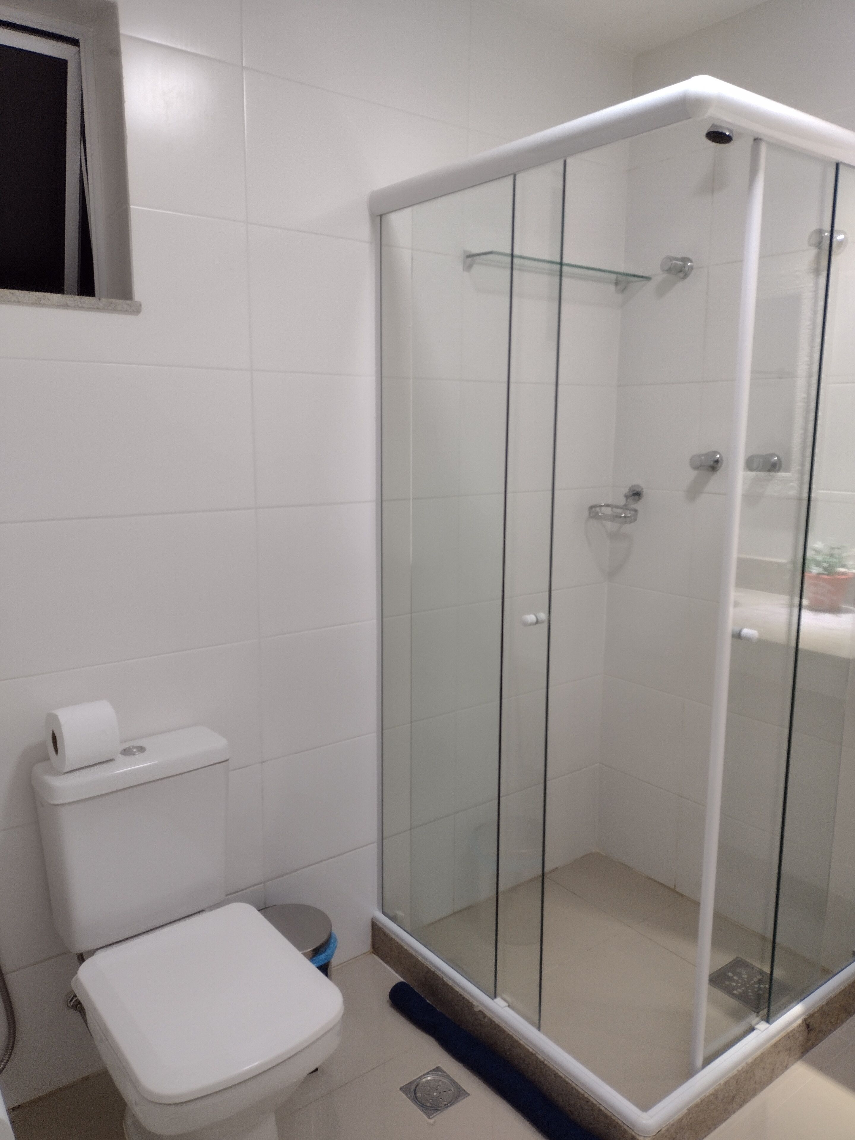 Ein Badezimmer mit Duschkabine, Toilette und kleinem Fenster.