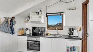 Een moderne keuken met witte kasten, een inbouwoven, een spoelbak en een raam met uitzicht op de omgeving.