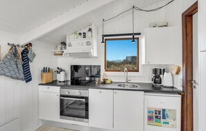 A modern kitchen with white cabinetry, a built-in oven, a sink, and a window with a view of the outdoors.