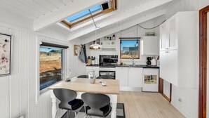 Een moderne keuken met dakraam, een eethoek met twee stoelen en uitzicht op het omliggende landschap.
