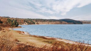 A coastal landscape with a beach, a small group of people, and a forested hill in the background. - Cozy home in Knebel with house sea view (Knebel)