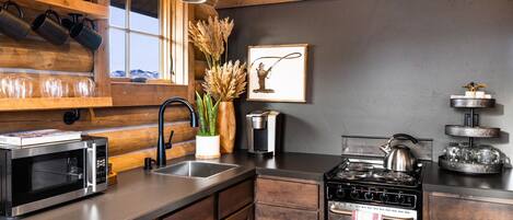 A modern kitchen with wooden cabinetry, a stainless steel stove, a microwave, and a sink.