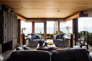 Un salon moderne doté d’une grande fenêtre donnant sur la mer, et aménagé avec des canapés et une table basse.