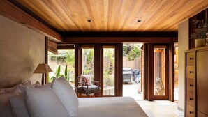 Een slaapkamer met een groot bed, houten plafond en uitzicht naar buiten.