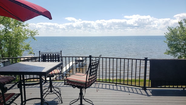 Une terrasse dotée de mobilier d’extérieur, notamment une table et des chaises, donnant sur une étendue d’eau.