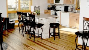 Une cuisine avec des meubles en bois, un îlot central doté de tabourets, un four à micro-ondes et une cuisinière.