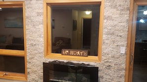 Un salon avec un mur en pierre, une cheminée, un miroir et un canapé.