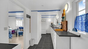 A modern kitchen with a black countertop, white cabinets, and a window with lace curtains. - 1 bedroom beautiful home in Hjørring (Hjørring)