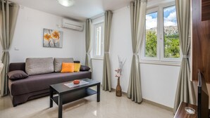 A living room with a sofa, a coffee table, and a window with curtains. - Stunning apartment in Baska with WiFi (Baska)