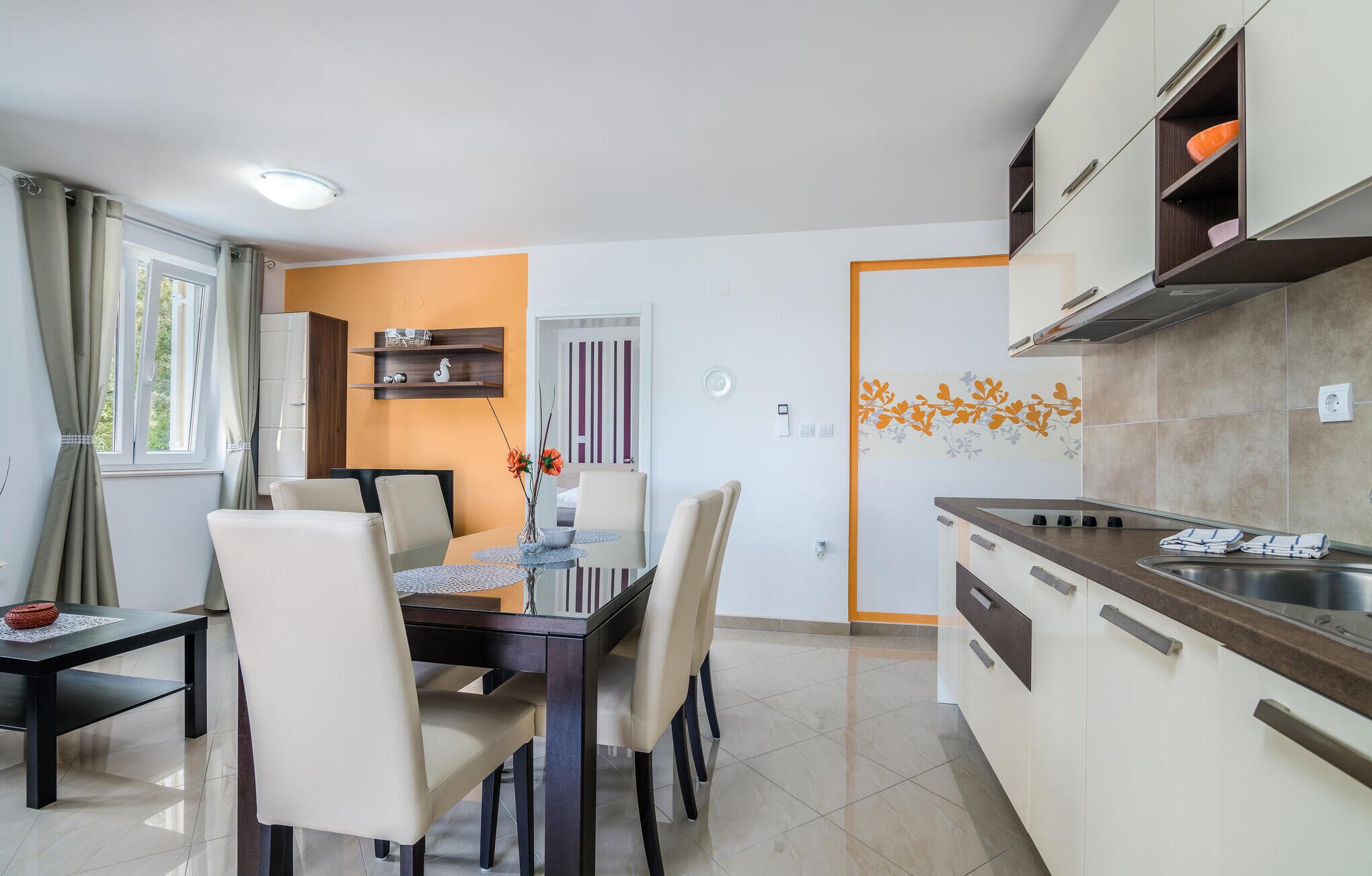 Une cuisine moderne avec un coin repas, comprenant une table ronde, des chaises et un four encastré.