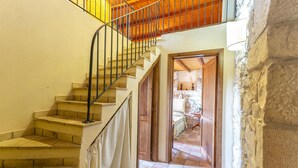 A staircase with a metal railing leading to a wooden ceiling. A door opens to a room with a stone wall and a tiled floor. - Stunning home in Ragusa (Ragusa)
