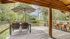 A wooden deck with a table and chairs, an umbrella, and a flag.