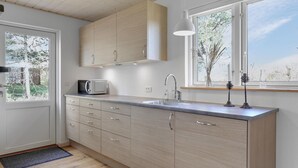 A modern kitchen with wooden cabinets, a stainless steel sink, and a microwave. - 3 bedroom stunning home in Nexø (Nexø)