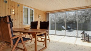 A wooden interior with a round table and chairs, large windows, and a view of the outdoors. - 3 bedroom stunning home in Nexø (Nexø)