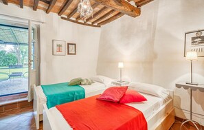 Une chambre avec deux lits, un plafond en bois, une porte donnant sur un espace extérieur et un mur orné de tableaux.