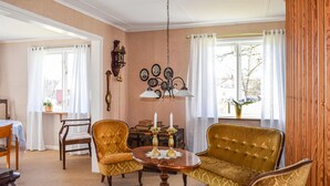 Una habitació amb un sofà antic, dos butaques, una taula de centre de fusta i una làmpada de cristall.