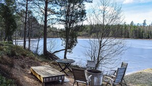 Zona d'estar a la vora del llac, amb taula, cadires i una xemeneia.