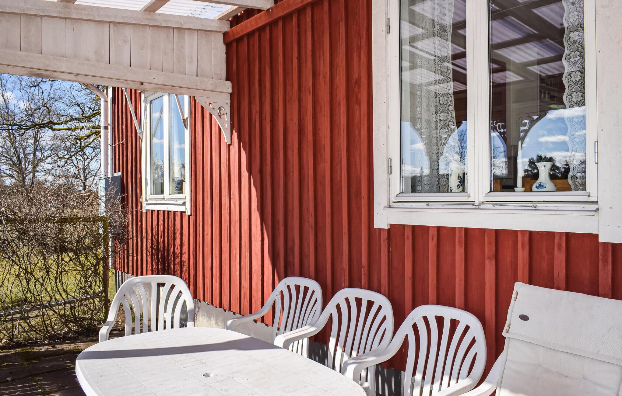 A red building with white-framed windows and a covered patio area with a table and chairs.