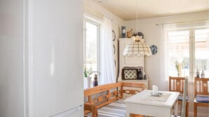 Una habitació acollidora amb una banca de fusta, una taula amb cadires i una làmpada penjant.