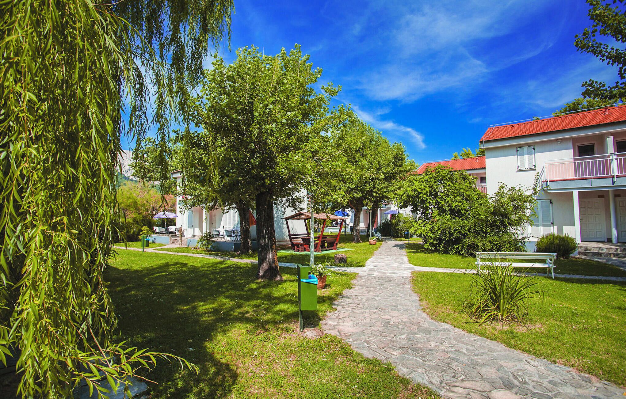 A pathway leading to a row of houses with a clear blue sky above.