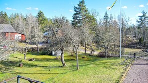En park med en flaggstång, träd, en röd byggnad och en gräsyta.