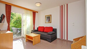 A living room with a sofa, a wooden coffee table, a TV, and a sliding glass door leading to an outdoor area. - 1 bedroom beautiful apartment in Baska (Baska)
