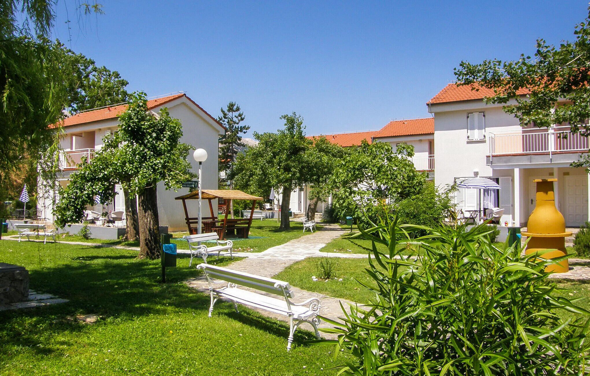 A courtyard with a white bench, a yellow water fountain, and a picnic table.