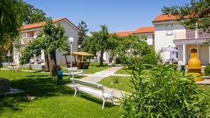 A courtyard with a white bench, a yellow water fountain, and a picnic table. - 1 bedroom beautiful apartment in Baska (Baska)