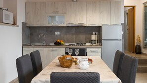 A modern kitchen with light wood cabinets, a stainless steel sink, and a dining table set with chairs. - Beautiful home in Orihi with WiFi (Orihi)