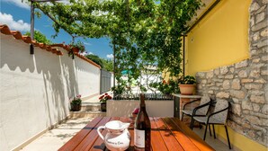A wooden table with a wine bottle, a teapot, and potted plants on a balcony with a stone wall and a yellow wall in the background. - Beautiful home in Orihi with WiFi (Orihi)
