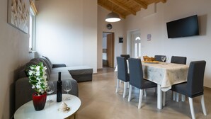 A dining area with a table set for four, a sofa, and a potted plant. - Beautiful home in Orihi with WiFi (Orihi)